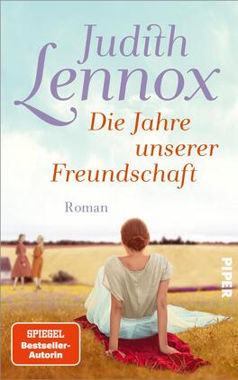 Das Buchcover zeigt eine weite, sonnendurchflutete Landschaft mit zwei Figuren im Vordergrund, die in ruhiger Pose miteinander sprechen. Die dominierenden Farben sind sanfte Pastelltöne, hauptsächlich Gelb, Blau und Lila, die eine harmonische Atmosphäre schaffen. Oben steht in eleganter Schrift „Judith Lennox“ und darunter in rötlicher Schrift „Die Jahre unserer Freundschaft“. Am unteren Rand ist das Wort „Roman“ sowie ein Hinweis auf die Autorin als „SPIEGEL Bestseller-Autorin“ zu sehen.