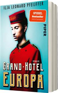 Das Buchcover zeigt einen jungen Mann in einer roten Uniform eines Hotelportiers mit einer Kappe, elegant und nachdenklich schauend. Der Hintergrund ist in einem sanften Türkis gehalten, was eine einladende Atmosphäre schafft. Der Titel „GRAND•HOTEL EUROPA“ ist in großen, weißen, modernen Lettern zentriert platziert. Oben links befindet sich ein oranger Kasten mit der Aufschrift „SPIEGEL Bestseller. Jetzt als Taschenbuch“. Der Autor Ilja Leonard Pfeijffer ist in kleinerer Schrift oben am Cover abgedruckt.