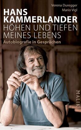 Hans Kammerlander – Höhen und Tiefen meines Lebens Das Buchcover zeigt ein Porträt von Hans Kammerlander. Er sitzt relaxed an einem Holztisch und blickt nachdenklich, während er die Hände ornamentiert in seiner Nähe hält. Der Hintergrund ist unscharf und besteht aus warmen Holztönen, die eine einladende Atmosphäre schaffen. Der Titel „HÖHEN UND TIEFEN MEINES LEBENS“ steht in großen, weißen Buchstaben oben, darunter sind die Namen der Autorinnen Verena Duregger und Mario Vigl in kleinerer Schrift zu sehen. Die Schrift ist modern und klar, das gesamte Cover strahlt eine ruhige, authentische Stimmung aus.
