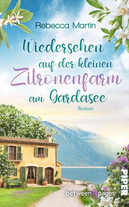 Lemon Blossoms – Wiedersehen in der kleinen Zitronenfarm am Gardasee Das Buchcover zeigt ein sonniges Gardasee-Motiv mit einem gelblichen Landhaus mit grünen Fensterläden, Zitronenbäumen und blühenden weißen Zweigen am oberen Rand, vor blau-türkisem See und sanften Bergen. Die Typografie kombiniert eine klare serifenlose Schrift für „Rebecca Martin“ und geschwungene, handschriftliche Schriftzüge in Türkis, Lavendel und Grün für den Titel. Stimmung: idyllisch, warm und mediterran.