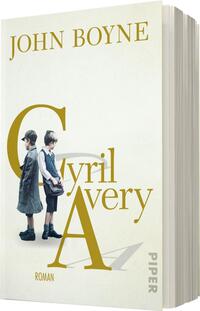 Das Buchcover zeigt zwei Jungen in historischen Kleidungsstücken, die Rücken an Rücken stehen. Die Farbpalette ist hell und freundlich, überwiegend in Weiß, mit goldenen und schwarzen Akzenten. Der Titel „Cyril Avery“ befindet sich in großen, stilisierten Buchstaben, wobei das „C“ und das „A“ hervorgehoben sind. Der Name des Autors „John Boyne“ steht in kleineren Buchstaben oben auf dem Cover. Am unteren Ende ist das Wort „Roman“ vermerkt sowie das Verlagslogo „PIPER“.