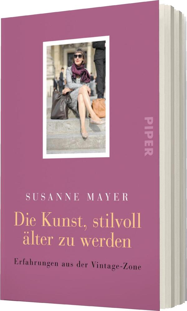 Das Buchcover zeigt einen eleganten, lilafarbenen Hintergrund. In der Mitte befindet sich ein rechteckiges, weiß umrandetes Bild einer stilvoll gekleideten Frau mit Sonnenbrille, die lässig auf einer Treppe sitzt und eine große Handtasche trägt. Der Titel „Die Kunst, stilvoll älter zu werden“ ist in goldener Schrift platziert, während der Autor „Susanne Mayer“ in weißer Schrift darüber steht. Am unteren Rand steht der Zusatz „Erfahrungen aus der Vintage-Zone“. Die Farbwahl und die Bildsprache vermitteln eine Atmosphäre von Stil und Lebensfreude.