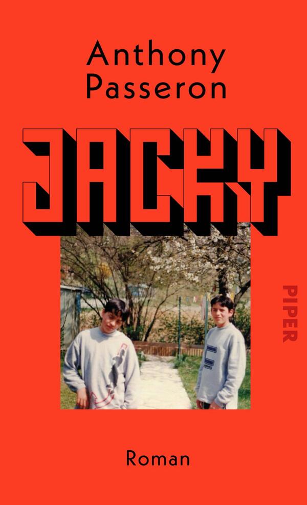 Das Buchcover zeigt einen leuchtend roten Hintergrund. Im oberen Bereich ist der Autor „Anthony Passeron“ in einer schlichten, schwarzen Schrift platziert. Der Titel „JACKY“ dominiert das Cover in großen, fetten Buchstaben, die in verschiedenen Schattierungen von Schwarz und Grau gestaltet sind und eine dreidimensionale Wirkung erzeugen. Unten rechts steht in kleinerer Schrift „PIPER“ und darunter die Kategorie „Roman“. Im Hintergrund sind zwei Jugendliche in lässiger Kleidung abgebildet, umgeben von einer grünen Landschaft mit blühenden Bäumen.