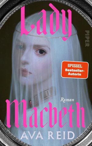 Das Buchcover zeigt ein oval gerahmtes Porträt einer blassen Frau mit langen weißen Haaren und durchscheinendem Schleier, ihr Blick melancholisch und geisterhaft. Farben dominieren helles Porzellanweiß, düsteres Grünoliv und ein silberner Rahmen. Der Titel „Lady Macbeth“ steht in großen, leuchtend pinken, gotisch anmutenden Lettern; darunter der Autorenname Ava Reid in weißen Großbuchstaben. Auf der rechten Seite ein oranger Aufkleber mit dem Text „SPIEGEL Bestseller-Autorin“. Klein steht „Roman“.