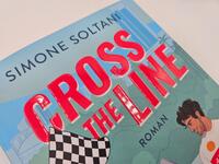 Außenansicht des Buches „Cross the Line – Auf der Rennstrecke kämpft er um den Sieg, im Leben um ihr Herz“