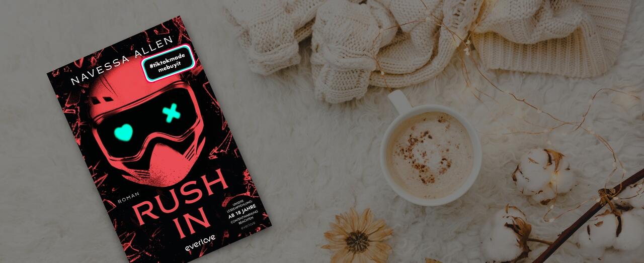 „Rush in“ von Navessa Allen liegt auf einem weißen, felligen Untergrund. Daneben eine Wollpulli, eine Tasse Kaffee und ein Baumwoll-Ast.