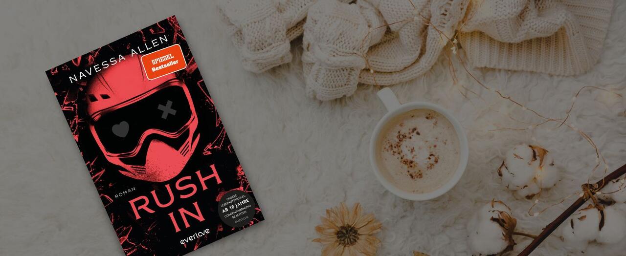 „Rush in“ von Navessa Allen liegt auf einem weißen, felligen Untergrund. Daneben eine Wollpulli, eine Tasse Kaffee und ein Baumwoll-Ast.