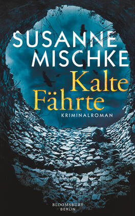 Das Buchcover zeigt einen dunklen Höhlen-Eingang, umgeben von steinigen Wänden. Die Farben sind überwiegend in Blau- und Grautönen gehalten, was eine kühle, mysteriöse Stimmung vermittelt. Der Titel „Kalte Fährte“ ist in großen, goldenen Buchstaben prominent platziert, während darüber der Autorennamen „Susanne Mischke“ in weißer Schrift erscheint. Am unteren Rand steht „Kriminalroman“ in schlichter, kleinerer Schrift. Einige schwarze Vögel fliegen in den Himmel, was die spannungsgeladene Atmosphäre verstärkt.