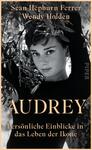 Das Buchcover zeigt eine Schwarz-Weiß-Fotografie von einer Frau mit einem sanften Lächeln, umgeben von grünen Olivenzweigen. Sie trägt einen schwarzen Rollkragenpullover und blickt direkt in die Kamera. Der Titel „AUDREY“ ist in großen, goldenen Buchstaben in der Mitte platziert, darunter steht der Untertitel „Persönliche Einblicke in das Leben der Ikone“ in kleinerer, heller Schrift. Die beiden Autoren, Sean Hepburn Ferrer und Wendy Holden, sind oben in eleganter, weißer Schrift angeführt. Die Atmosphäre ist nostalgisch und stilvoll.