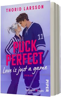 Das Buchcover zeigt ein nahes, romantisches Seitenporträt eines Eishockeyspielers in dunkelblauem Trikot mit der Nummer 11 und eines Schiedsrichterinnen-ähnlichen Frauentyps in schwarz-weiß gestreiftem Hemd, die sich an der Stirn berühren. Hintergrund in kühlen Violett- und Blautönen, großer pinker Titel „PUCK PERFECT“, weißer Untertitel „Love is just a game“, oben der Autorenname „THORID LARSSON“ in Pink. Atmosphäre: leichte, verspielte Romantik.