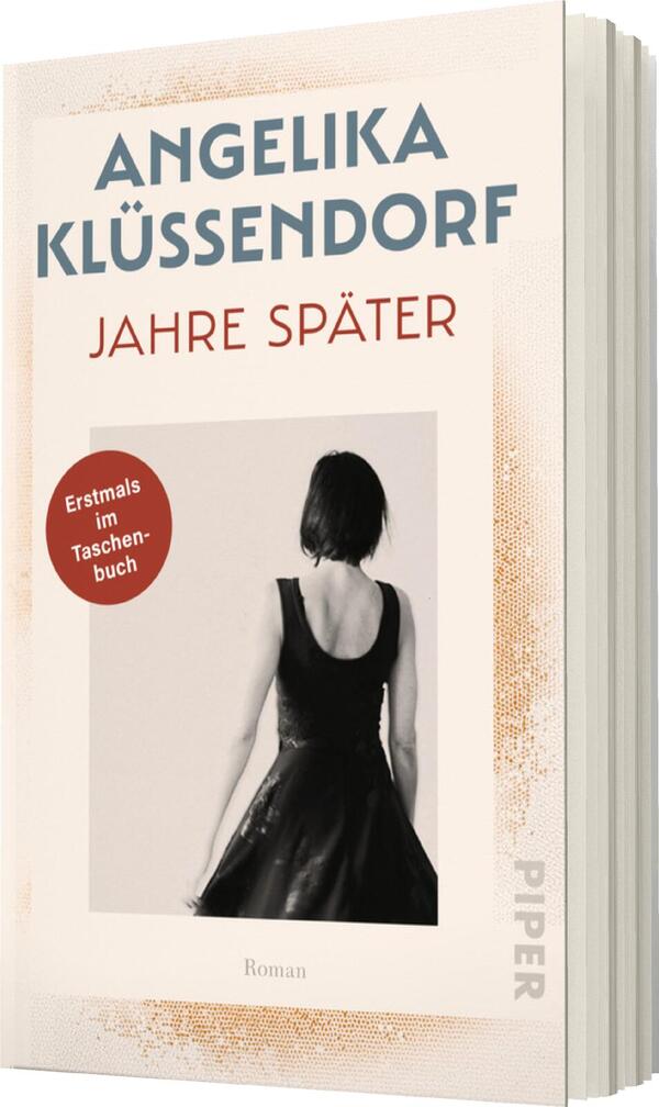 Das Buchcover zeigt eine elegante, monochrome Fotografie einer Frau mit schwarzem Kleid, die von hinten abgebildet ist. Sie hat kurze, dunkle Haare und steht vor einem hellen, leicht strukturierten Hintergrund. Oben in großen, hellblauen Buchstaben steht „ANGELIKA KLÜSSENDORF“. Darunter in einer kräftigen, roten Schrift ist der Titel „JAHRE SPÄTER“ zu sehen. Ein roter Kreis mit dem Text „Erstmals im Taschenbuch“ hebt sich ab. Am unteren Rand steht in kleinerer Schrift „Roman“.