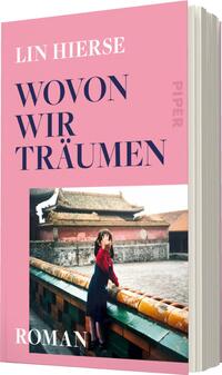 Das Buchcover zeigt einen rosafarbenen Hintergrund mit dem Titel „WOVON WIR TRÄUMEN“ in großer, eleganter Schrift in Dunkelblau. Der Autorname, Lin Hierse, befindet sich am oberen Rand in einer etwas kleineren Schriftgröße. In der unteren Hälfte ist ein Foto einer jungen Frau zu sehen, die in einem roten Kleid an einem historischen Ort steht und mit einer Hand ihr Gesicht verdeckt. Dies vermittelt eine geheimnisvolle und träumerische Atmosphäre. Am unteren Rand ist das Wort „ROMAN“ in verschnörkelter Schrift platziert.