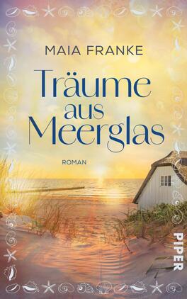 Das Buchcover zeigt eine sanfte Küstenlandschaft bei Sonnenuntergang. Im Vordergrund ist ein helles Strandhaus zu sehen, umgeben von goldenen Sanddünen und grasbewachsenen Flächen. Der Titel „Träume aus Meerglas“ ist in eleganter, geschwungener Schrift in Blau gehalten, wobei die Schriftzüge teilweise überlappend sind. Der Autorenname „Maia Franke“ steht in einer schmaleren Schrift darüber. Die Farbpalette umfasst warme Gelbtöne und sanfte Blautöne, die eine verträumte Atmosphäre erzeugen.