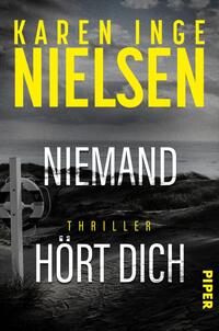 Das Buchcover zeigt eine düstere Küstenlandschaft in Graustufen, mit aufgewühltem Wasser und einem Strand, der von einem einsamen Pfosten mit einem weißen Kreuz markiert wird. Der Titel „Niemand hört dich“ ist in großen, fett gedruckten Buchstaben in Weiß und Gelb gehalten, wobei das Wort „Niemand“ hervorgehoben wird. Unter dem Titel steht „Thriller“ in weniger auffälligem Gelb. Der Name der Autorin, Karen Inge Nielsen, befindet sich oben in kräftigem Gelb. In der unteren Ecke ist das Verlagslogo „Piper“ abgebildet.