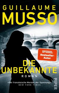 Das Buchcover zeigt eine düstere Silhouette einer Frau vor einer Brücke, die sich über einen Fluss spannt. Der Hintergrund ist in kühlen Grautönen gehalten, während der Titel „DIE UNBEKANNTE“ in leuchtendem Gelb hervorsticht. Darüber steht der Autor „GUILLAUME MUSSO“ ebenfalls in Gelb, und rechts oben befindet sich ein rotes Feld mit dem Text „SPIEGEL Bestseller-Autor“. Die Typografie vermittelt eine spannende und mysteriöse Atmosphäre.