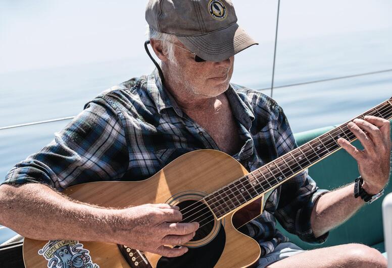 Marc Bielefeld mit Gitarre auf seinem Segelboot