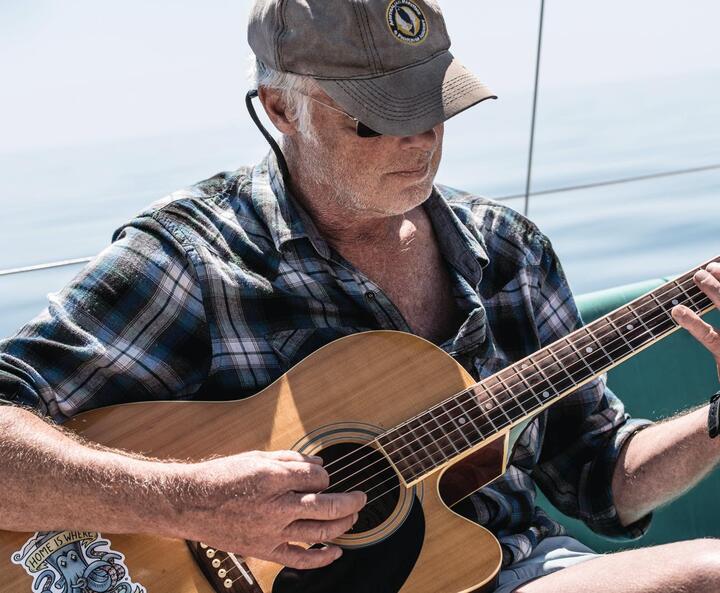 Marc Bielefeld mit Gitarre auf seinem Segelboot