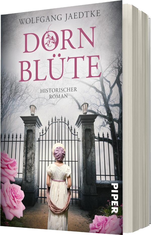 Das Buchcover zeigt eine historische Szene mit einer weiblichen Figur, die von hinten zu sehen ist. Sie trägt ein schlichtes, helles Kleid und einen rosafarbenen Haarreif. Im Hintergrund sind ein großes, offenes Tor und kahle Baumstämme, die eine melancholische Atmosphäre erzeugen. Der Titel „DORNBLÜTE“ ist in satter, pinkfarbener Typografie oben platziert, während darunter in kleinerer Schrift „HISTORISCHER ROMAN“ steht. Rosa Blumen umrahmen das untere Bild.