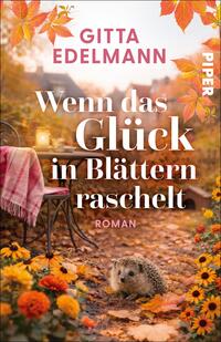 Das Buchcover zeigt eine herbstliche Gartenszene bei goldenem Licht: im Vordergrund ein Igel zwischen orange-gelben Blumen und fallenden Blättern. Links ein schmales Metall-Bistrotisch mit rosa-weißem Plaid und eine Laterne im unscharfen Hintergrund. Titel „Wenn das Glück in Blättern raschelt“ steht groß in weißer Serifenschrift, Autorenname Gitta Edelmann oben in kräftigem Pink, darunter klein „Roman“.