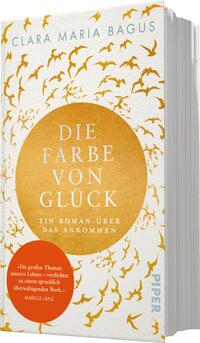 Das Buchcover zeigt einen weißen Hintergrund, auf dem ein großer, goldener Kreis im Mittelpunkt steht. Innerhalb des Kreises ist der Titel „DIE FARBE VON GLÜCK“ in eleganter, serifenloser Schrift in kräftigem Schwarz platziert. Darunter steht der Untertitel „Ein Roman über das Ankommen“ in etwas kleinerer Schrift. Darüber ist der Autorinnenname „CLARA MARIA BAGUS“ inHellblau zu sehen. Um den goldenen Kreis fliegen stilisierte, goldene Vögel, was eine freudige und inspirierende Atmosphäre vermittelt. In der unteren linken Ecke befindet sich eine rote Sprechblase mit dem Zitat „Die großen Themen unseres Lebens …“.