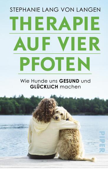 Das Buchcover zeigt eine Frau mit langen, offenen Haaren, die mit ihrem Hund am Ufer eines ruhigen Gewässers sitzt. Beide blicken auf die Natur. Der Titel „THERAPIE AUF VIER PFOTEN“ steht in großen, grünen Buchstaben und vermittelt Freundlichkeit. Darunter befindet sich der Untertitel „Wie Hunde uns GESUND und GLÜCKLICH machen“ in einer schlichteren Typografie. Der Hintergrund zeigt einen klaren Himmel und eine bewaldete Landschaft, die eine entspannte und positive Atmosphäre ausstrahlt. 