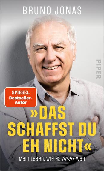 Das Buchcover zeigt das lächelnde Gesicht von Bruno Jonas, der in einem hellblauen Hemd abgebildet ist. Der Hintergrund ist hell und schlicht gehalten. Oben ist der Titel „Das schaffst du eh nicht“ in großen, gelben Buchstaben platziert, unterhalb steht der Untertitel „Mein Leben, wie es nicht war“ in kleinerer, grauer Schrift. In der oberen linken Ecke befindet sich ein rotes Feld mit dem Text „SPIEGEL Bestseller-Autor“. Die Typografie ist modern und gut lesbar, was zur positiven Atmosphäre des Covers beiträgt.