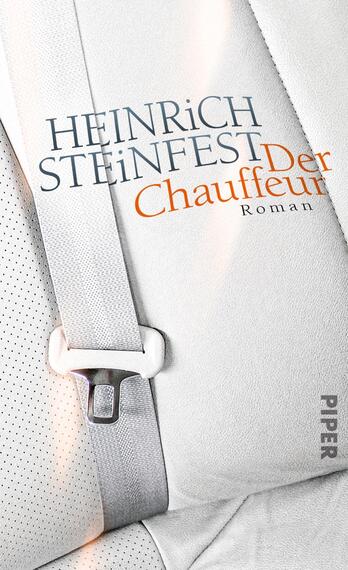 Das Buchcover zeigt einen hellen Autositz mit einem angeschnallten Sicherheitsgurt. Die Oberfläche des Sitzes ist mit einem feinen, perforierten Muster versehen. Oberhalb des Autositzes steht in großem, blauem Text der Autor „HEINRICH STEINFEST“. Darunter ist in auffälligem orangefarbenem Schriftzug der Titel „Der Chauffeur“ platziert, gefolgt vom Wort „Roman“ in kleinerer Schrift. Die Farbgebung vermittelt eine moderne und klare Atmosphäre.