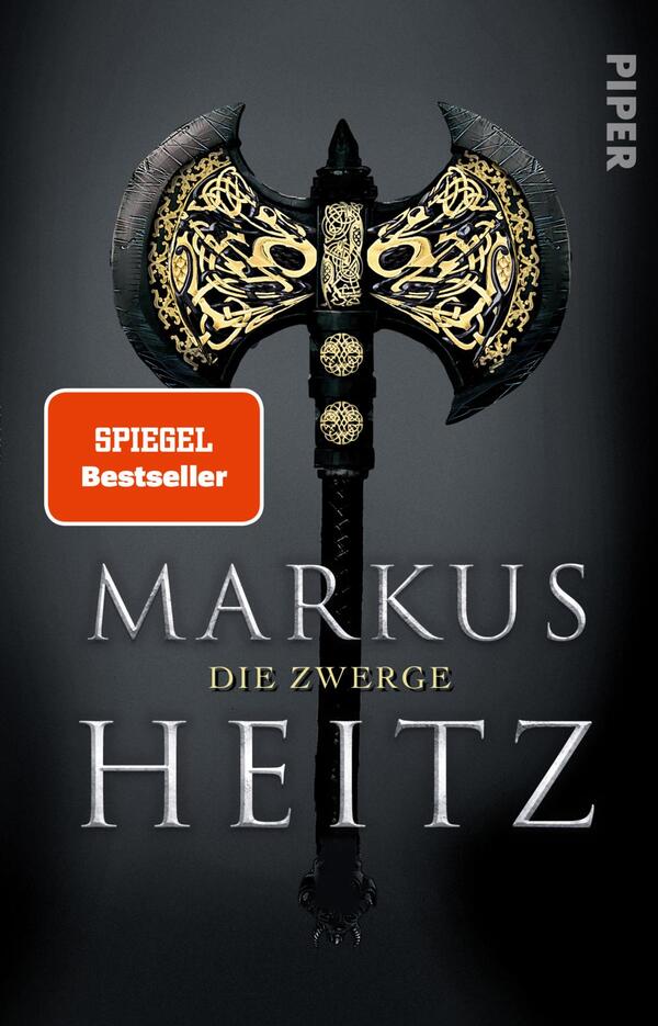 Das Buchcover zeigt eine imposante, kunstvoll verzierte Doppeläxte vor einem dunklen, einfarbigen Hintergrund. Die Äxte sind in Schwarz und Gold gehalten und strahlen eine kraftvolle Eleganz aus. Der Titel „DIE ZWERGE“ von Markus Heitz ist in großen, silbernen Buchstaben in der Mitte platziert, während der Autorname „MARKUS HEITZ“ darunter in etwas kleinerer Schrift erscheint. Ein rotes, rechteckiges Label mit der Aufschrift „SPIEGEL Bestseller“ befindet sich in der oberen linken Ecke des Covers.