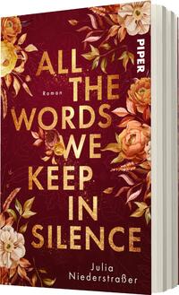 Das Buchcover zeigt einen kräftigen, dunklen Rotton als Hintergrund, der mit floralen Motiven in sanften Gelb- und Cremetönen verziert ist. Im Zentrum des Covers steht der Titel „ALL THE WORDS WE KEEP IN SILENCE“ in großen, goldenen Buchstaben, die einen schimmernden Effekt erzeugen. Unter dem Titel ist der Schriftzug „Roman“ in kleinerer Schriftgröße platziert. Am unteren Rand ist der Name der Autorin „Julia Niederstraßer“ in dezentem, weißem Schriftzug zu sehen.