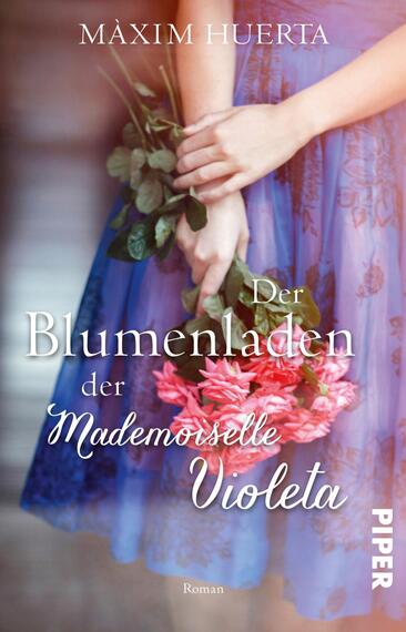 Das Buchcover zeigt eine Frau in einem fließenden, lila Kleid, die einen Strauß aus pinken und weißen Blumen in Händen hält. Der Hintergrund ist unscharf und vermittelt eine warme, einladende Atmosphäre. Der Titel „Der Blumenladen der Mademoiselle Violeta“ ist in eleganter, geschwungener Schrift, weiß und gut lesbar, im unteren Drittel platziert. Der Autorenname „Màxim Huerta“ steht darüber in schlichter, heller Typografie. Die Farbwahl und Komposition erzeugen ein Gefühl von Romantik und Leichtigkeit.