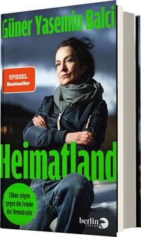 Das Buchcover zeigt eine ernste Frau mit dunklem Haar, die in einer lässigen Jacke und einem Schal gekleidet ist und in die Kamera blickt. Der Hintergrund ist in gedämpften Grautönen gehalten, was die Aufmerksamkeit auf die Figur lenkt. Der Titel „Heimatland“ erscheint in großen, leuchtend grünen Buchstaben im oberen Bereich des Covers. Unterhalb des Titels steht in kleinerer Schrift „Zähne zeigen gegen die Feinde der Demokratie“, ebenfalls in grün. Die Gesamtatmosphäre vermittelt Entschlossenheit und Nachdenklichkeit.
