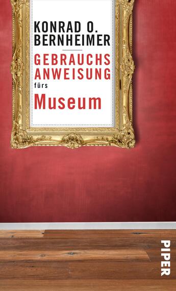 Das Buchcover zeigt einen goldenen Bilderrahmen auf rotem Hintergrund. Im Rahmen befindet sich der Titel „Gebrauchsanweisung fürs Museum“ in großer, moderner Typografie, wobei das Wort „Gebrauchsanweisung“ in schwarzer und „Museum“ in roter Schrift hervorgehoben ist. Der Name des Autors, „Konrad O. Bernheimer“, steht im oberen Bereich in schwarzer Schrift. Der Fußbereich des Covers zeigt einen hellen Holzfußboden.
