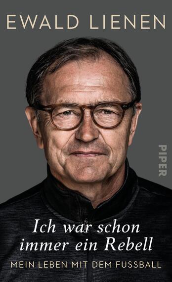 Das Buchcover zeigt ein Porträt von Ewald Lienen, einem älteren Mann mit Brille und einem freundlichen, zugleich nachdenklichen Gesichtsausdruck. Er trägt ein schwarzes Outfit und hat leicht graue Haare. Der Hintergrund ist in einem dunklen Grauton gehalten. Oberhalb des Porträts steht in eleganter, goldfarbener Schrift der Name „Ewald Lienen“. Darunter in weißer Schrift: „Ich war schon immer ein Rebell“. Am unteren Rand des Covers steht der Untertitel „Mein Leben mit dem Fussball“ ebenfalls in weißer Schrift.