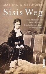 Das Buchcover zeigt eine historische Fotografie einer jungen Frau in eleganter, schwarzer Kleidung mit einem weißen Kragen und einer Hochsteckfrisur. Sie sitzt auf einem Stuhl und legt ihren Arm auf einen Hund. Der Hintergrund ist neutral und hell gehalten. Der Titel „Sisis Weg“ steht in großen, weißen Buchstaben oben, während der Untertitel „Vom Mädchen zur Frau – Kaiserin Elisabeths erste Jahre am Wiener Hof“ in kleinerer Schrift darunter platziert ist. Der Name der Autorin, Martina Winkelhofer, befindet sich oben links.