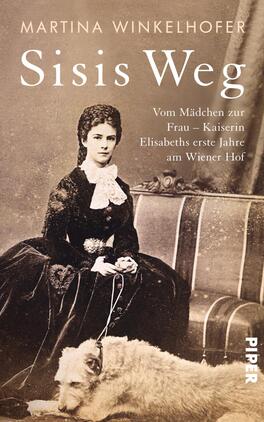 Das Buchcover zeigt eine historische Fotografie einer jungen Frau in eleganter, schwarzer Kleidung mit einem weißen Kragen und einer Hochsteckfrisur. Sie sitzt auf einem Stuhl und legt ihren Arm auf einen Hund. Der Hintergrund ist neutral und hell gehalten. Der Titel „Sisis Weg“ steht in großen, weißen Buchstaben oben, während der Untertitel „Vom Mädchen zur Frau – Kaiserin Elisabeths erste Jahre am Wiener Hof“ in kleinerer Schrift darunter platziert ist. Der Name der Autorin, Martina Winkelhofer, befindet sich oben links.