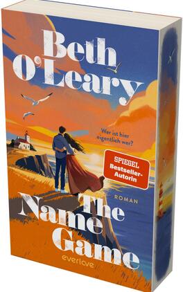 Das Buchcover zeigt ein Paar, eng umschlungen auf einer Klippenkante im Sonnenuntergang, Blick aufs Meer mit Leuchtturm links; warme Orange‑ und Blautöne dominieren, Möwen fliegen am Himmel. Titel „The Name Game“ groß in weißer Serifenschrift, oben Autorin „Beth O’Leary“ ebenfalls weiß; gelber Untertitel „Wer ist hier eigentlich wer?“. Roter Aufkleber „SPIEGEL Bestseller‑Autorin“. Atmosphäre: romantisch und leicht nostalgisch.
