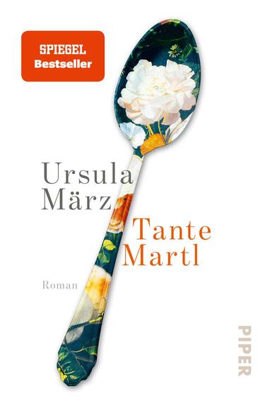 Das Buchcover zeigt einen großen Löffel mit floralem Muster in lebendigen Farben, der zentrale Element des Designs ist. Auf der linken Seite steht der Name der Autorin „Ursula März“ in eleganter, grauer Schrift, während der Titel „Tante Martl“ in auffälliger, oranger Schrift leicht schräg platziert ist. Unter dem Titel steht das Wort „Roman“ in kleinerer Schrift. Oben links ist ein rechteckiger, roter Hinweis auf einen „SPIEGEL Bestseller“ zu sehen.