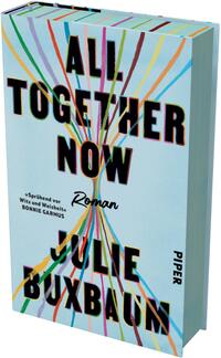 Das Buchcover zeigt vor hellblauem Grund den Titel „ALL TOGETHER NOW“ in großen, schwarzen Blockbuchstaben mit feinem gelben Schatten, überkreuzt von zahlreichen bunten, dünnen Linien (Gelb, Rot, Blau, Grün, Violett), die in der Bildmitte zusammenlaufen. Unter dem Titel steht in handschriftlicher Schrift „Roman“. Unten groß der Autorname „JULIE BUXBAUM“. Links ein kurzer Zitatverweis „Sprühend vor Witz und Weisheit. – Bonnie Garmus“.