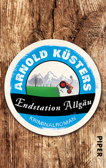 Das Buchcover zeigt einen runden, kreisförmigen Ausschnitt vor einem rustikalen Holzuntergrund. Der obere Teil ist in einem strahlenden Blau gehalten und trägt den Schriftzug „ARNOLD KÜSTERS“ in weißen, gut lesbaren Buchstaben. Unterhalb des blauen Abschnitts steht der Titel „Endstation Allgäu“ in schwarzer Schrift auf einem weißen Banner. Darunter befindet sich die Aufschrift „KRIMINALROMAN“ in kleinerer, ebenfalls schwarzer Schrift. Im Zentrum ist eine Landschaft mit einem Traktor und schneebedeckten Bergen angedeutet, was eine ländliche, spannende Atmosphäre vermittelt.