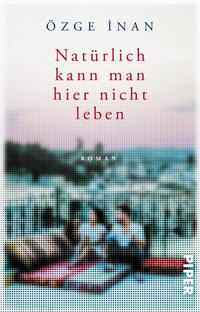 Das Buchcover zeigt eine unscharfe, verträumte Szenerie mit zwei Figuren, die auf einem Teppich sitzen und den Blick auf eine Stadtlandschaft richten. Der Hintergrund ist in sanften Rosa- und Blautönen gehalten, was eine melancholische Atmosphäre vermittelt. Der Titel „Natürlich kann man hier nicht leben“ ist zentral in kräftigem Rot platziert, während der Autorennamen „Özge İnan“ in einem eleganten dunklen Blau oben steht. Der Untertitel „Roman“ ist dezent in Kleinbuchstaben abgedruckt.