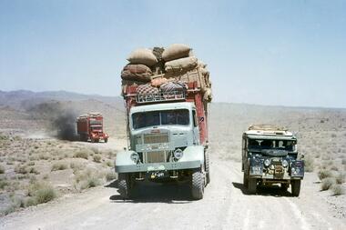 Land Rover neben einem LKW auf einer Wüstenstraße