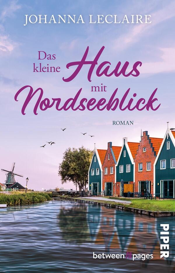 Das Buchcover zeigt eine malerische Küstenlandschaft mit einem ruhigen Wasserlauf im Vordergrund. Links ist eine Windmühle abgebildet, während rechts farbenfrohe Häuser mit grünen und roten Dächern stehen. Der Himmel ist in sanften Pastelltönen gehalten, mit einigen fliegenden Vögeln. Der Titel „Das kleine Haus mit Nordseeblick“ erscheint in geschwungener, pinker Schrift, während der Zusatz „Roman“ in dezentem Grau geschrieben ist. Oben steht der Autorenname „Johanna Leclaire“.