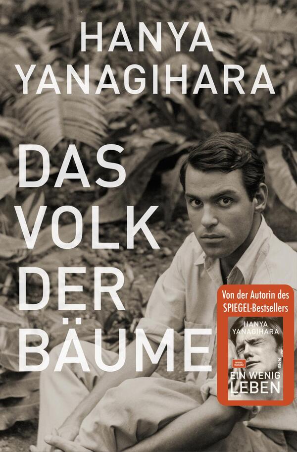 Das Buchcover zeigt einen schwarz-weißen Hintergrund mit einem jungen Mann, der in die Kamera blickt, umgeben von üppiger Pflanzenwelt. Der Titel „DAS VOLK DER BÄUME“ ist in großen, weißen Buchstaben prominent platziert. Der Autor Hanya Yanagihara ist in kleinerer, weißer Schrift über dem Titel zu sehen. In der unteren rechten Ecke befindet sich ein rotes Etikett mit dem Text „Von der Autorin des SPIEGEL-Bestsellers EIN WENIG LEBEN“.