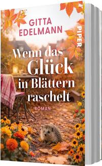 Das Buchcover zeigt eine warme, herbstliche Szene in Orange- und Goldtönen mit fallenden Blättern. Im Vordergrund liegt ein Igel zwischen bunten Blumen und Laub, dahinter ein Stuhl mit rosa-kariertem Plaid und eine Laterne. Der Titel „Wenn das Glück in Blättern raschelt“ ist groß, weiß und serifenbetont, der Autorenname Gitta Edelmann steht oben in Versalien, pinkfarben. Stimmung: gemütlich, nostalgisch.