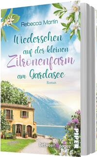 Das Buchcover zeigt eine sonnige, idyllische Szene am Gardasee mit einem warmgelben Landhaus am Ufer, einem schmalen Weg und blühenden Sträuchern. Im Hintergrund ragen blaue Berge unter hellem Himmel auf. Zitronenblüten und grüne Blätter rahmen das Motiv. Der Titel ist in verspielter, teilkursiver Typografie gesetzt, teils Türkis, Lila und Grün; Autorin Rebecca Martin ist namentlich genannt.
