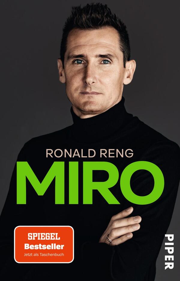 Das Buchcover zeigt eine Porträtaufnahme eines Mannes mit kurzem, dunklem Haar und einem entschlossenen Blick. Er trägt einen schwarzen Rollkragenpullover, der einen eleganten Kontrast zu dem neutralen Hintergrund bildet. Der Titel „MIRO“ ist in großen, kräftigen grünen Buchstaben prominently platziert. Darunter steht der Autor „RONALD RENG“ in kleinerer, weißer Schrift. Ein rotes Label weist auf den Status als „SPIEGEL Bestseller“ hin, mit dem Zusatz „Jetzt als Taschenbuch“ darunter, während das Verlagslogo am rechten Coverrand zu sehen ist.