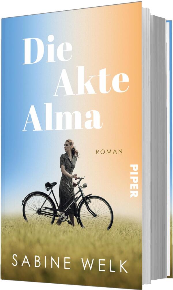 Das Buchcover zeigt einen sanften Farbverlauf von Blau links zu Orange rechts, darüber groß in weißer Serifenschrift der Titel „Die Akte Alma“, darunter klein der Schriftzug „Roman“. Im Vordergrund steht eine Frau in dunklem, zeitlosem Kleid neben einem schwarzen Fahrrad in hohem Gras, sie blickt nach rechts. Unten als Autorenname erscheint Sabine Welk. Stimmung: nostalgisch, ruhig und leicht melancholisch.