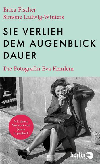Das Buchcover zeigt oben einen mintgrünen Block mit den Autorennamen Erica Fischer und Simone Ladwig‑Winters in pink sowie dem schwarzen, groß gesetzten Titel SIE VERLIEH DEM AUGENBLICK DAUER und dem Untertitel „Die Fotografin Eva Kemlein“ in pink. Darunter ein schwarzweißes Foto einer lächelnden Frau, die auf einer Treppenstufe sitzt und mit einer Kamera fotografiert; die Stimmung ist lebendig und dokumentarisch. Links unten ein pinker Kreis mit dem Text „Mit einem Vorwort von Jenny Erpenbeck“.