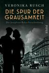 Das Buchcover zeigt eine mysteriöse Stadtlandschaft in gedämpften Grautönen. Im Vordergrund stehen zwei silhouettenhafte Figuren, die sich einander zuwenden. Der Titel „DIE SPUR DER GRAUSAMKEIT“ ist in bold orangefarbener Schrift prominent platziert, während darunter die Unterzeile „Die Josephine-Baker-Verschwörung“ in kleinerer, weißer Schrift erscheint. Der Name der Autorin „VERONIKA RUSCH“ steht oben in weißer Schrift. Der Verlag „PIPER“ ist dezent in der unteren rechten Ecke abgebildet. Die Atmosphäre vermittelt Spannung und Geheimnis.