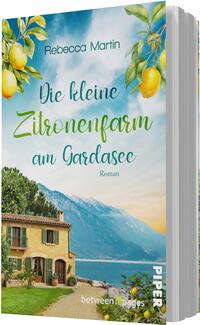 Das Buchcover zeigt eine malerische Landschaft am Gardasee mit einem Blick auf eine charmante, gelbe Villa und üppigen Zitronenbäumen. Im oberen Teil dominiert ein strahlend blauer Himmel mit sanften Wolken. Der Titel „Die kleine Zitronenfarm am Gardasee“ ist in eleganter, grüner Schrift gestaltet, während der Autorenname „Rebecca Martin“ dezent darüber platziert ist. Die Atmosphäre vermittelt ein Gefühl von Idylle und mediterranem Flair.